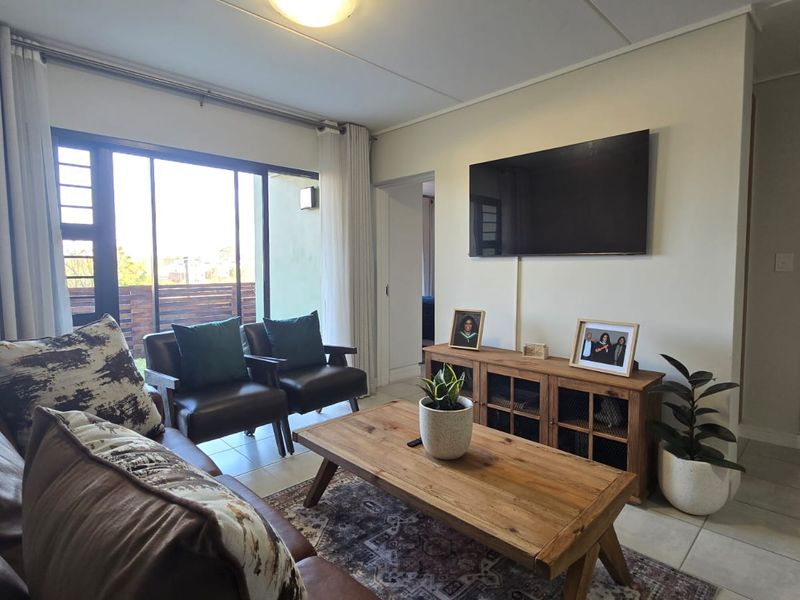 A well-lit living room featuring tiled flooring and a large sliding glass door providing access to an outdoor area.
