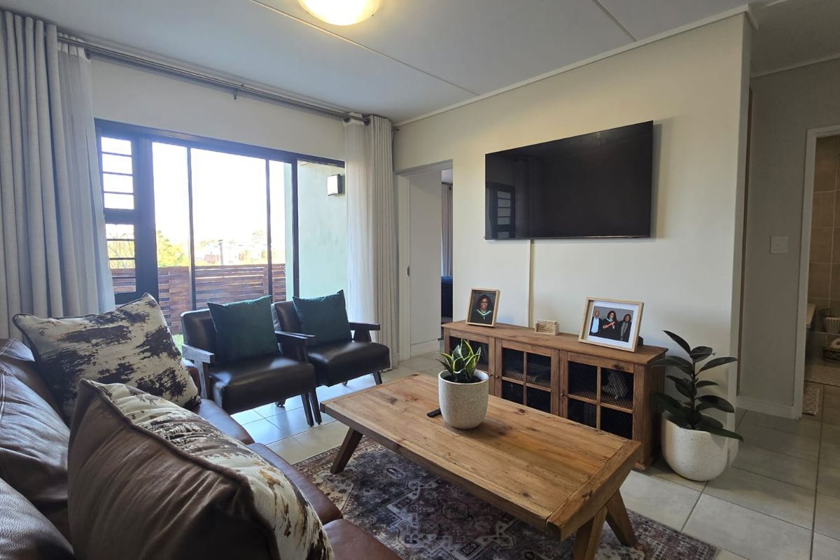 A well-lit living room featuring tiled flooring and a large sliding glass door providing access to an outdoor area.