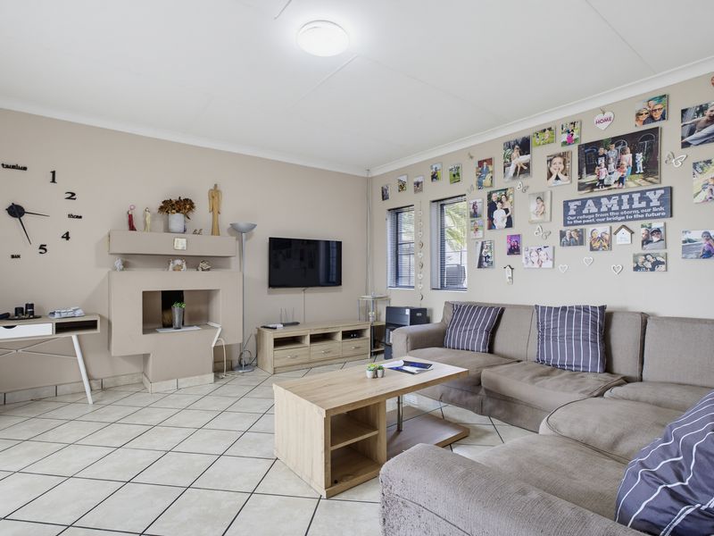 A spacious living room featuring tiled flooring, a built-in fireplace, and neutral wall tones, offering a comfortable and functional family living space.