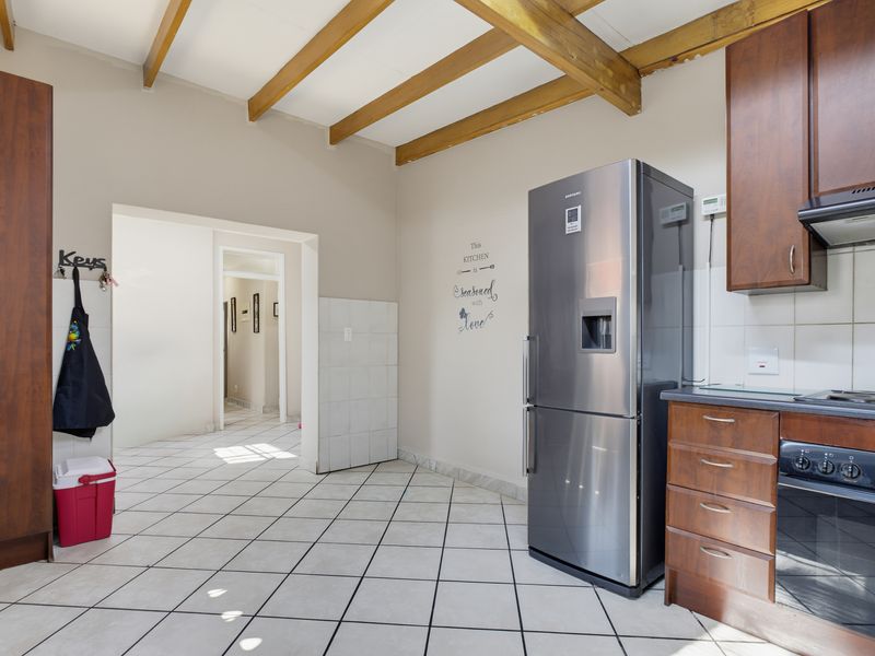 Kitchen featuring exposed timber ceiling beams, tiled flooring, and built-in cabinetry with integrated oven and hob.