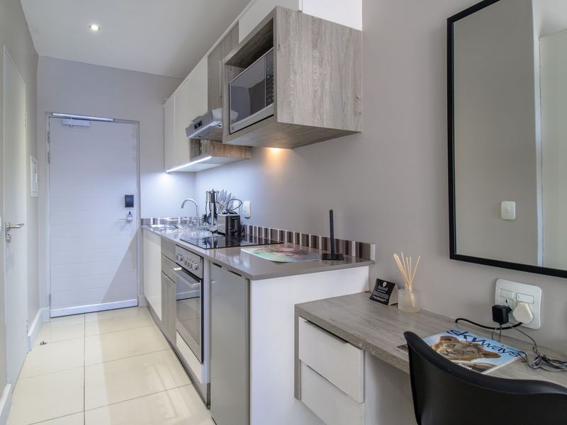 Compact modern kitchen featuring built-in cabinetry, integrated appliances, and a functional workspace area with tiled flooring.