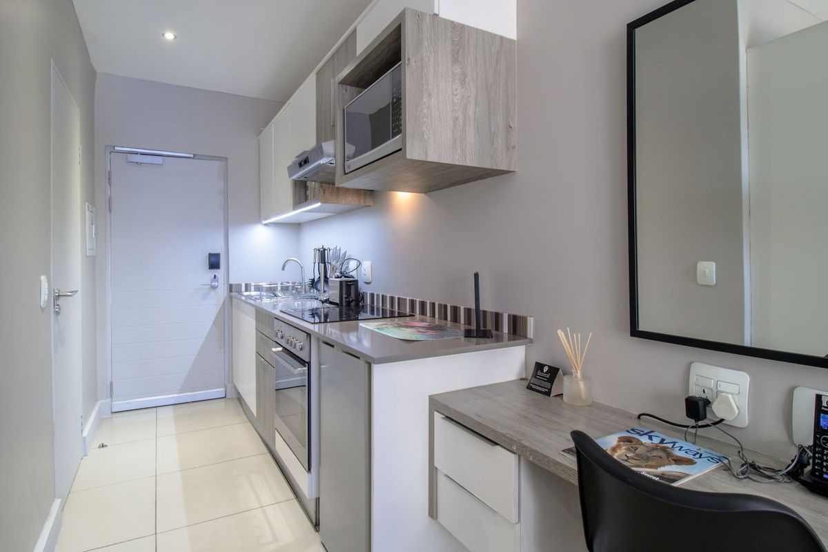 Compact modern kitchen featuring built-in cabinetry, integrated appliances, and a functional workspace area with tiled flooring.