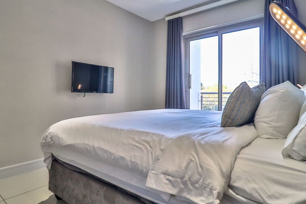 A well-maintained bedroom featuring tiled flooring and a sliding glass door providing access to an outdoor balcony area.