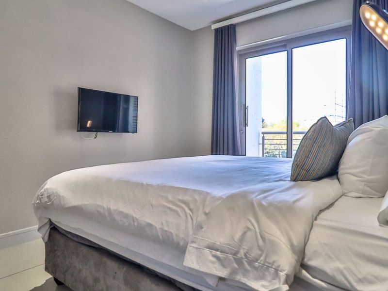 A well-maintained bedroom featuring tiled flooring and a sliding glass door providing access to an outdoor balcony area.