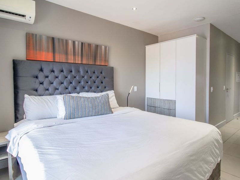 A well-maintained bedroom featuring tiled flooring, a built-in wardrobe, and a wall-mounted split-system air conditioner for climate control.