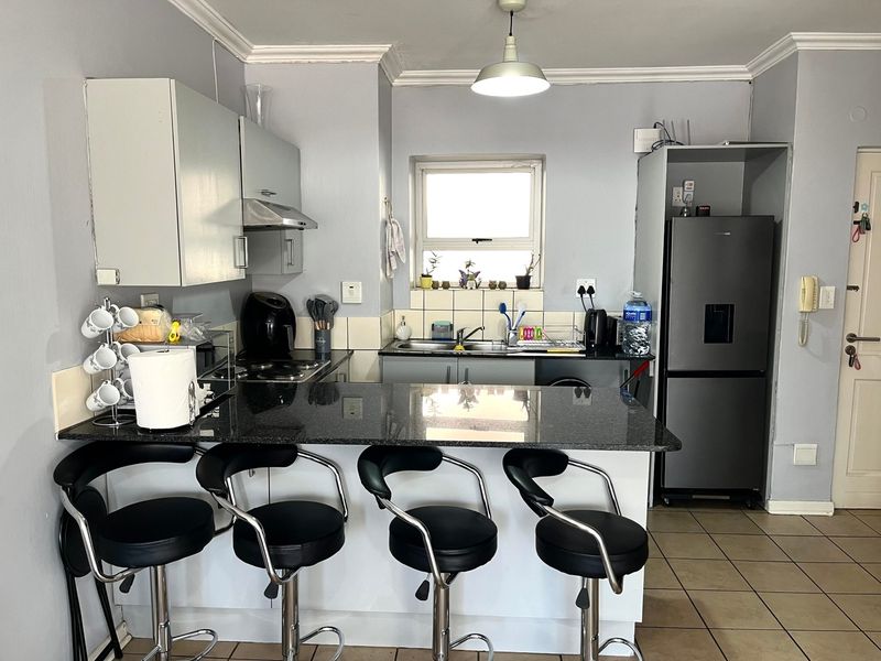 A functional kitchen featuring granite countertops, a breakfast bar, built-in cabinetry, and ceramic tile flooring, providing a practical layout for daily use.