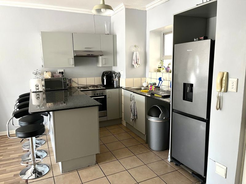 Functional kitchen featuring granite countertops, built-in oven, hob, extractor fan, and ample cabinetry with tiled flooring.