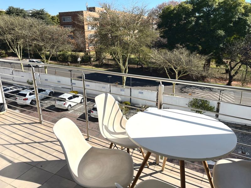 A balcony featuring tiled flooring and a stainless steel balustrade, offering an elevated view of the street and surrounding neighborhood.