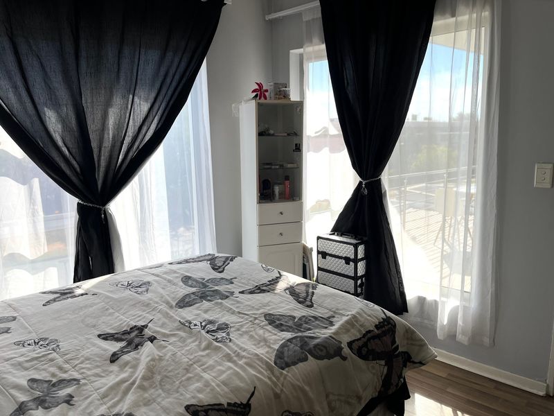 A bedroom featuring laminate flooring and large sliding glass doors that provide access to an outdoor balcony area.