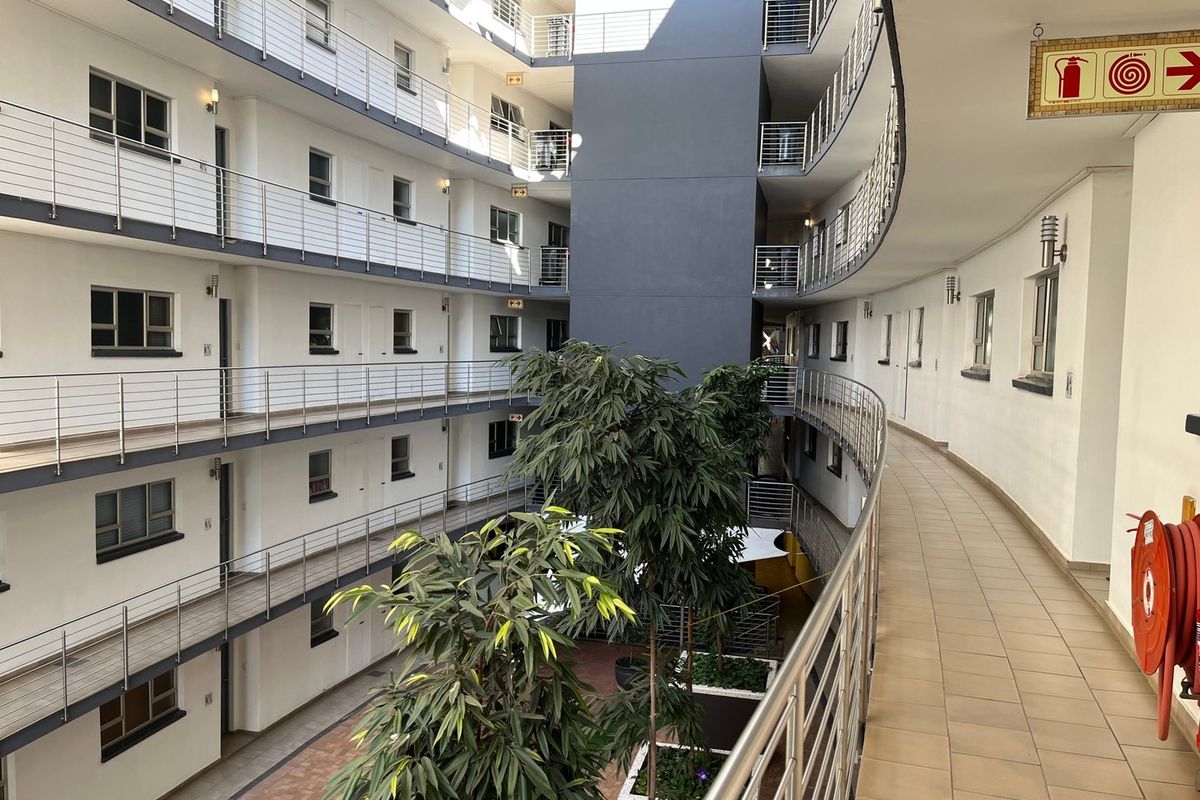A view of the apartment complex atrium featuring multi-level walkways with stainless steel balustrades and central courtyard landscaping.
