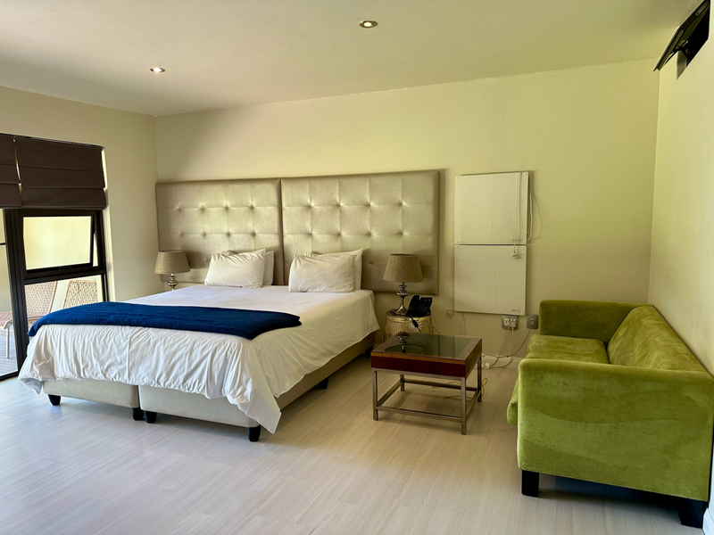 A well-maintained bedroom featuring laminate flooring, recessed downlighting, and a sliding door providing access to an outdoor area.