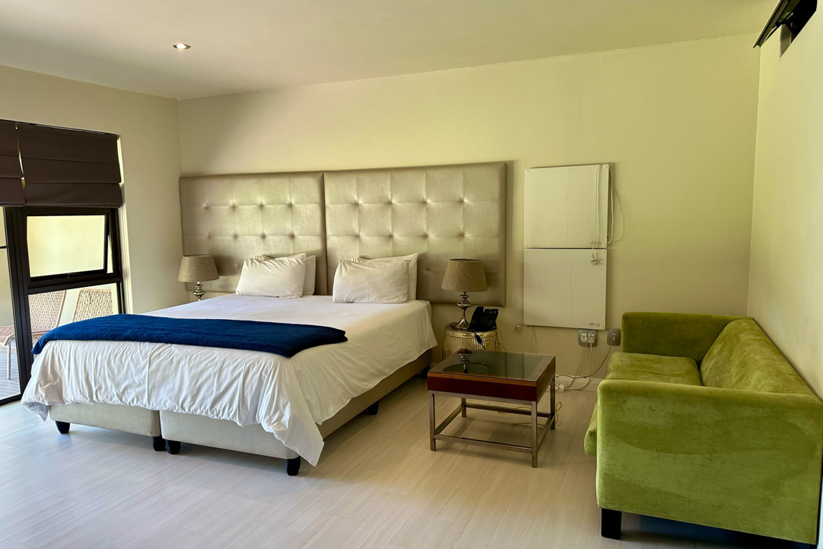 A well-maintained bedroom featuring laminate flooring, recessed downlighting, and a sliding door providing access to an outdoor area.