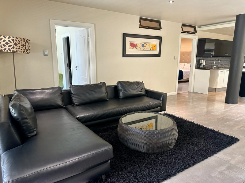 Open plan living area featuring tiled flooring, recessed lighting, and a view into the adjacent kitchen and bedroom.