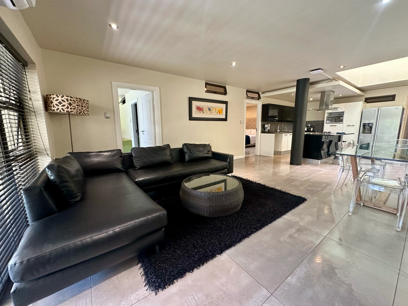 Spacious open-plan living and kitchen area featuring modern tiled floors, recessed lighting, and a sleek kitchen island with integrated appliances.