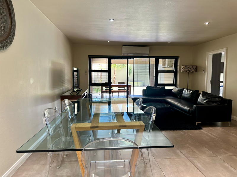 Spacious open-plan living and dining area featuring tiled floors, recessed lighting, and large sliding glass doors providing access to the outdoor patio.