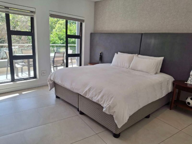Spacious bedroom featuring large windows, tiled flooring, and direct access to a private balcony.