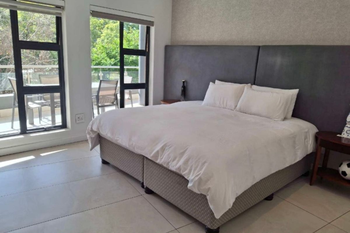 Spacious bedroom featuring large windows, tiled flooring, and direct access to a private balcony.
