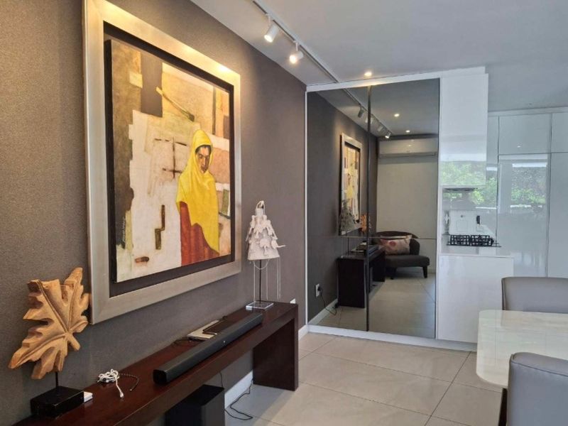 Modern open-plan living area featuring sleek tiled flooring, track lighting, and a large mirrored wall panel that enhances the sense of space.