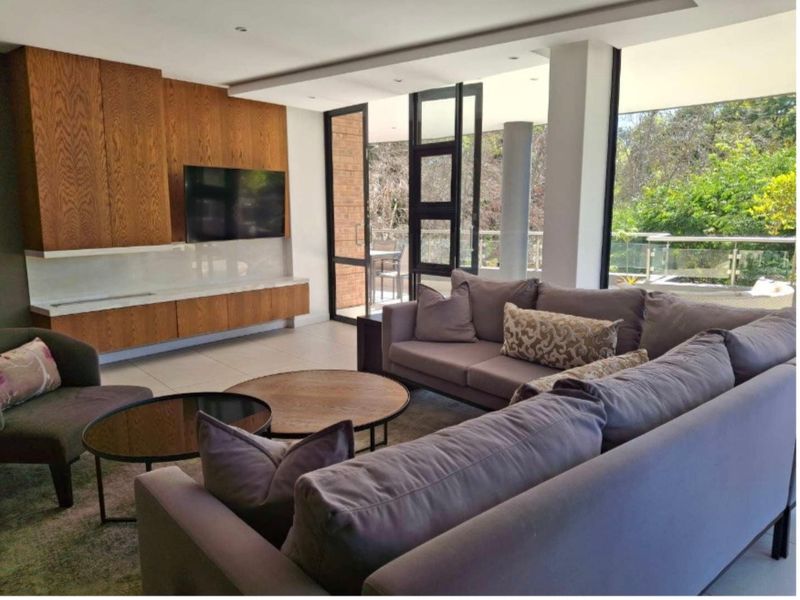 Modern living room featuring custom wood cabinetry, recessed lighting, and large glass doors opening to a balcony with scenic views.