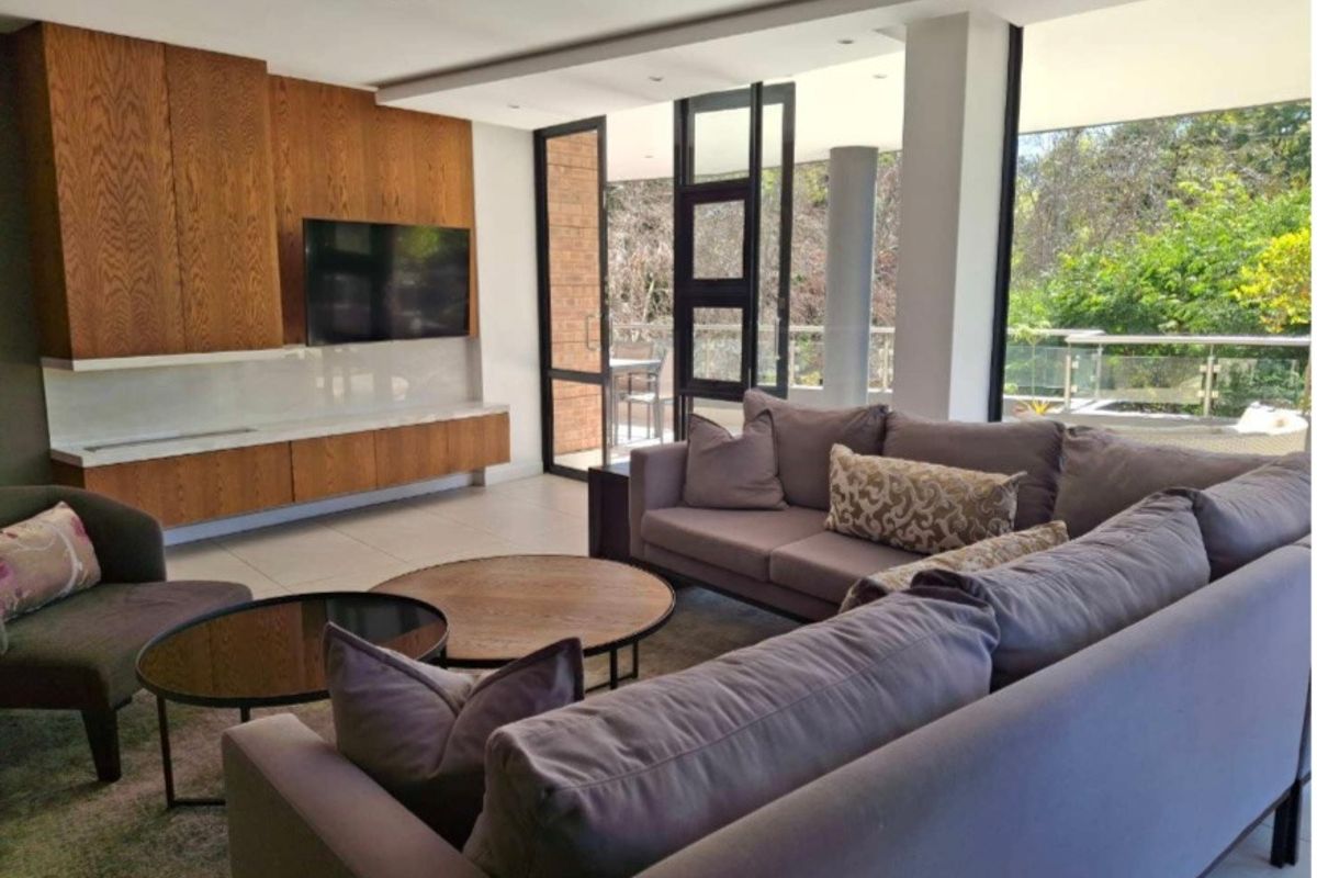Modern living room featuring custom wood cabinetry, recessed lighting, and large glass doors opening to a balcony with scenic views.