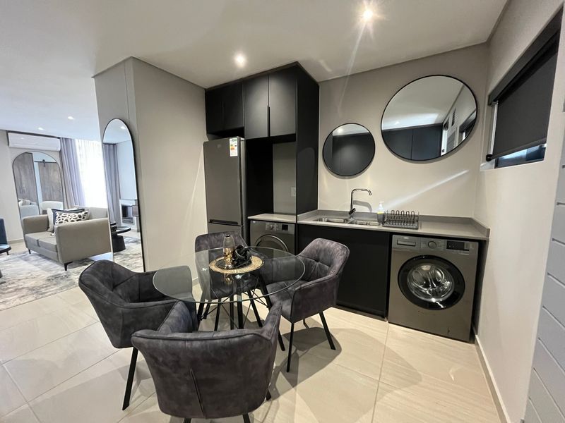 A modern, well-appointed laundry area featuring sleek dark cabinetry, integrated sink, and tiled flooring, seamlessly connected to the adjacent living space.