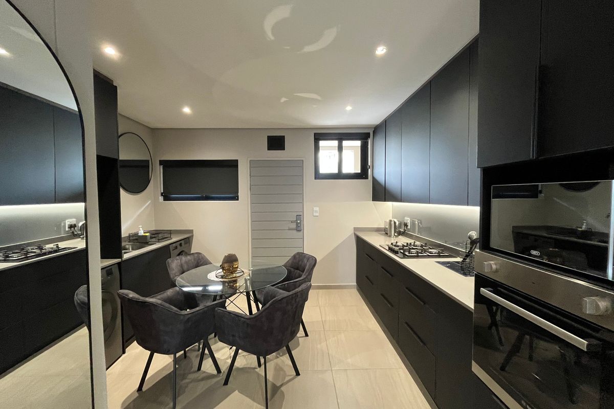 Modern kitchen featuring sleek dark cabinetry, stone countertops, integrated appliances, gas hob, and recessed lighting, creating a sophisticated and functional culinary space.