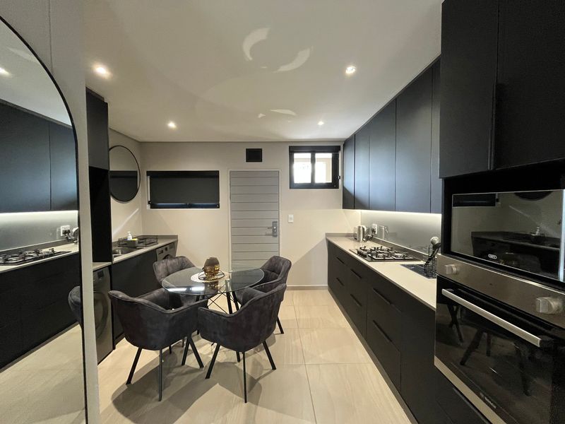 Modern kitchen featuring sleek dark cabinetry, stone countertops, integrated appliances, gas hob, and recessed lighting, creating a sophisticated and functional culinary space.