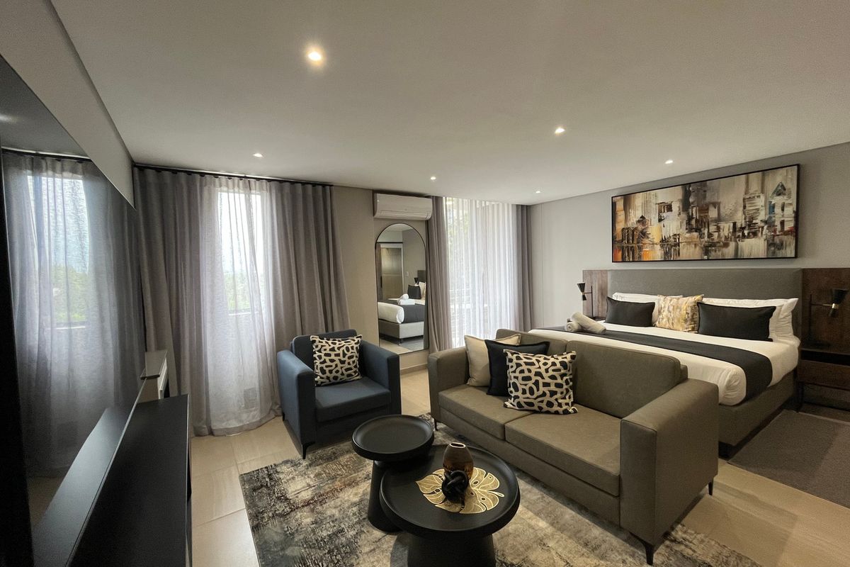 A spacious, modern bedroom featuring tiled flooring, recessed downlighting, and a wall-mounted split-system air conditioning unit.