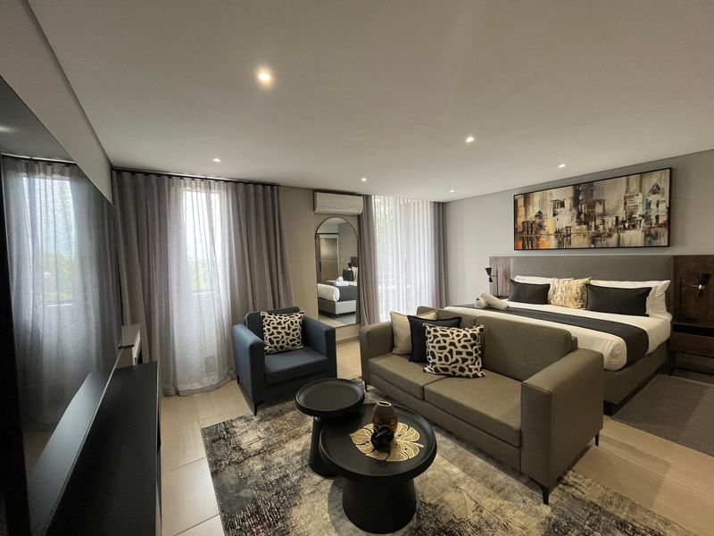 A spacious, modern bedroom featuring tiled flooring, recessed downlighting, and a wall-mounted split-system air conditioning unit.