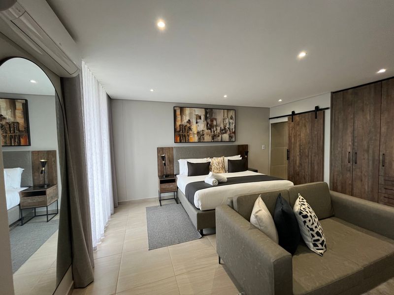 A modern, well-appointed bedroom featuring tiled flooring, built-in cabinetry, a sliding barn door, and integrated air conditioning.