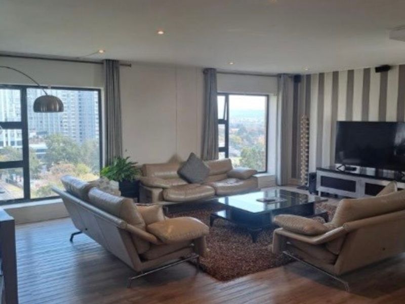Spacious living room featuring laminate flooring, recessed downlights, and large windows offering expansive city views.
