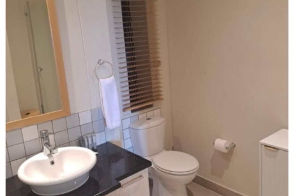 A clean, functional bathroom featuring a vanity with a granite countertop, vessel sink, and neutral tiled flooring.