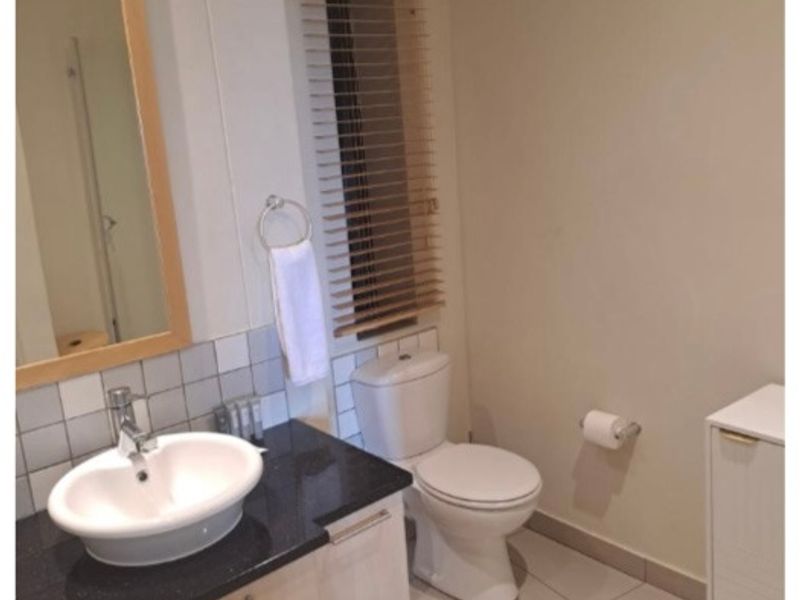A clean, functional bathroom featuring a vanity with a granite countertop, vessel sink, and neutral tiled flooring.
