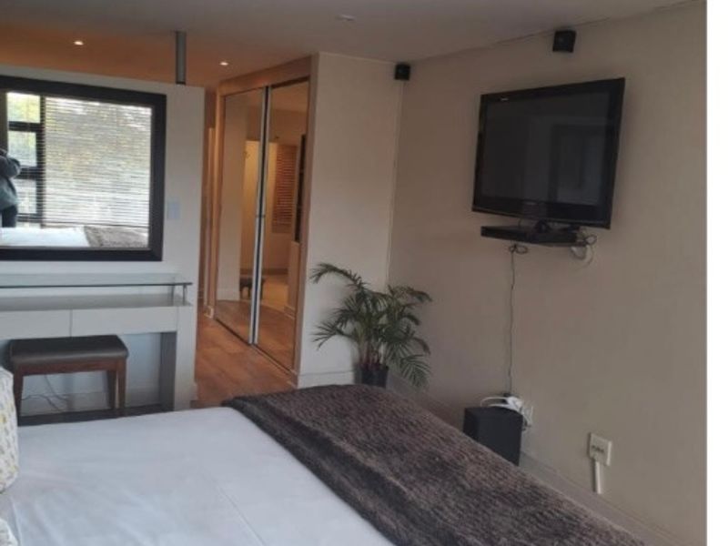 A well-maintained bedroom featuring built-in cupboards with mirrored sliding doors, recessed ceiling lighting, and neutral wall finishes.