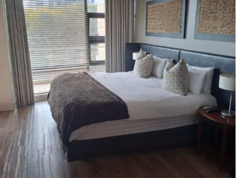 A well-maintained bedroom featuring laminate flooring, large windows with integrated blinds, and recessed ceiling lighting, offering a bright and comfortable living space.