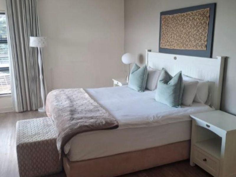 A well-maintained bedroom featuring laminate flooring, neutral wall tones, and recessed ceiling lighting, providing a comfortable and functional living space.