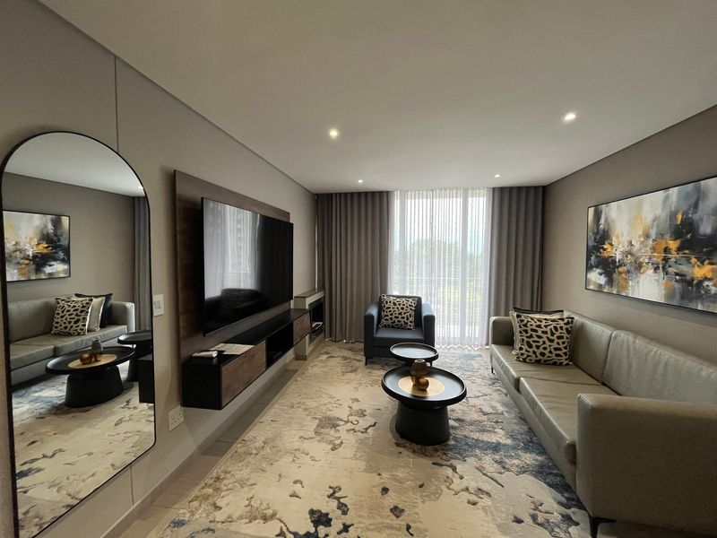 Modern living room featuring a built-in media console, recessed downlighting, and large windows with floor-to-ceiling curtains, creating a bright and contemporary atmosphere.