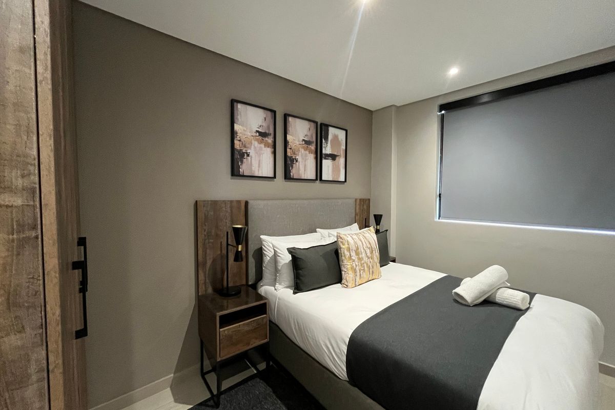 A modern, well-maintained bedroom featuring recessed downlighting, a roller blind, and built-in wardrobe storage.