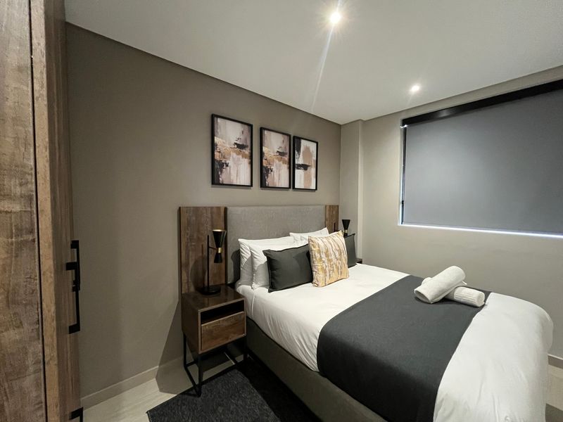 A modern, well-maintained bedroom featuring recessed downlighting, a roller blind, and built-in wardrobe storage.