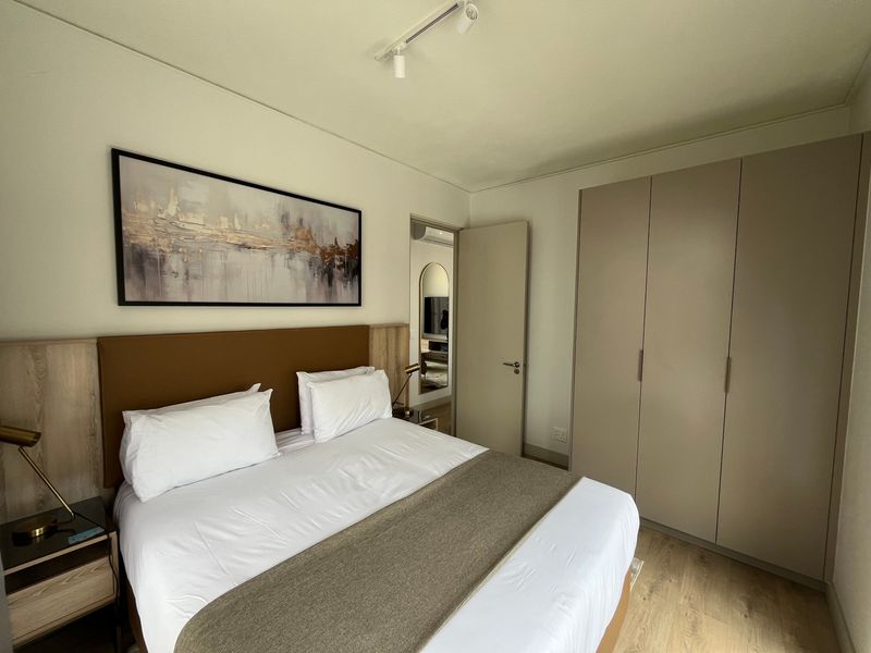 A well-maintained bedroom featuring neutral tones, built-in wardrobes, and modern track lighting, offering a clean and comfortable living space.