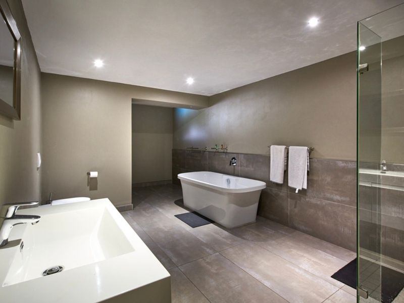 Modern bathroom featuring a freestanding bathtub, glass-enclosed shower, and a sleek vanity basin with contemporary finishes and recessed lighting.
