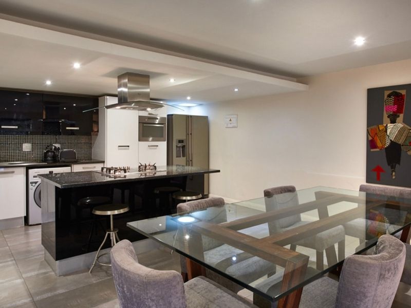 Modern open-plan kitchen and dining area featuring a sleek kitchen island with integrated hob, extractor fan, and contemporary cabinetry.