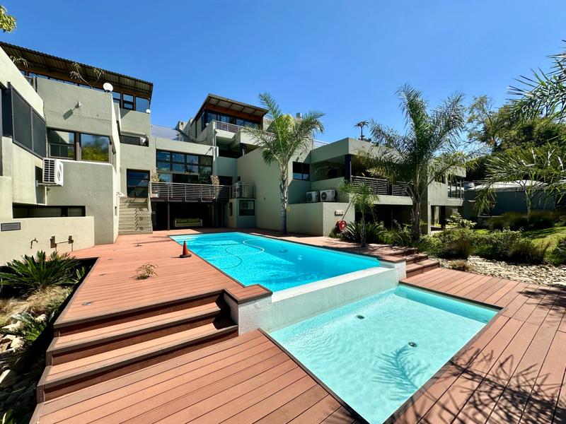 Spacious outdoor pool area featuring tiered timber decking, a swimming pool, and multi-level apartment architecture with balconies.