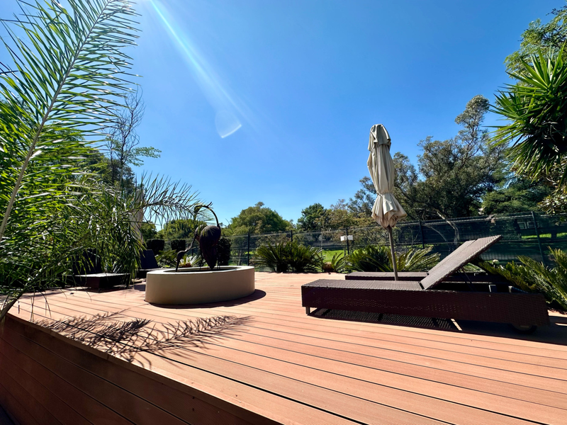 A well-maintained outdoor timber deck area featuring perimeter fencing and landscaped surroundings, ideal for relaxation.