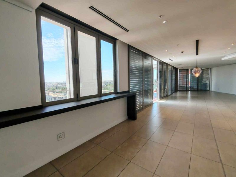 Spacious open-plan living area featuring large windows, tiled flooring, recessed lighting, and ducted air conditioning with expansive city views.