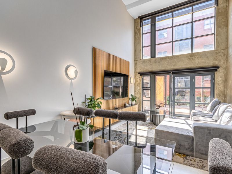 Modern open-plan living area featuring double-volume windows, a stylish timber slat feature wall, and high-quality finishes with abundant natural light.