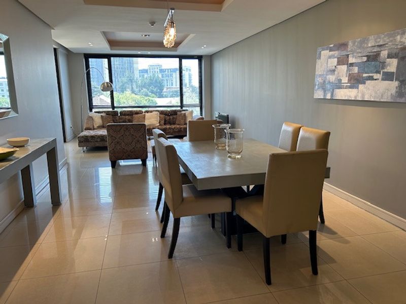 Spacious open-plan living and dining area featuring polished porcelain floor tiles, recessed ceiling details, and large windows providing ample natural light.