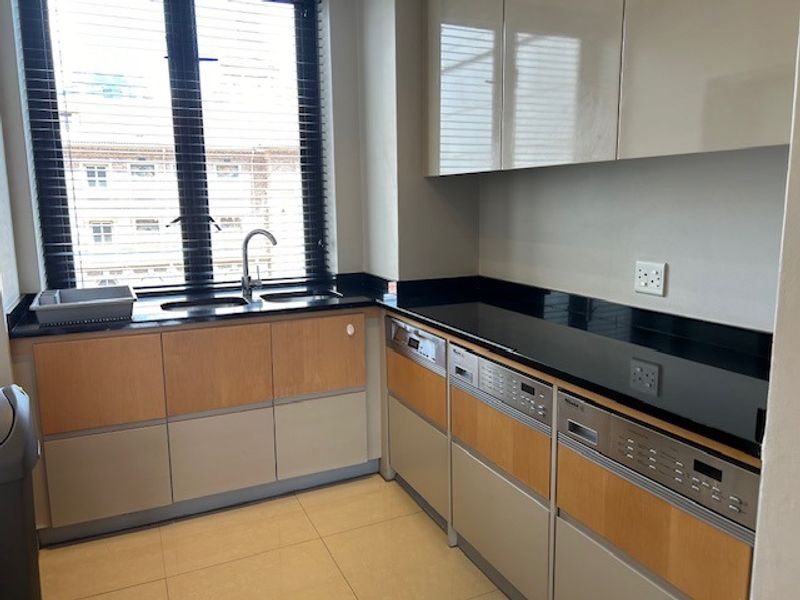 A functional scullery area featuring built-in cabinetry, granite countertops, an integrated dishwasher, and a sink positioned beneath a window.