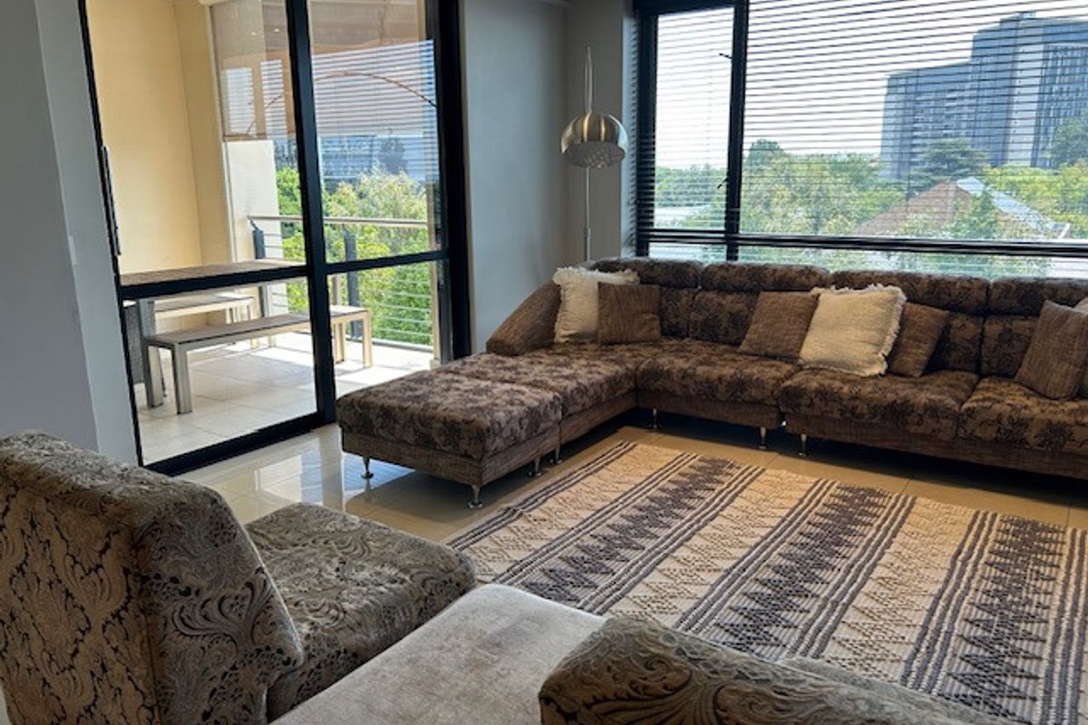 Spacious living room featuring large windows, tiled flooring, and sliding glass doors that open onto a private balcony with scenic views.