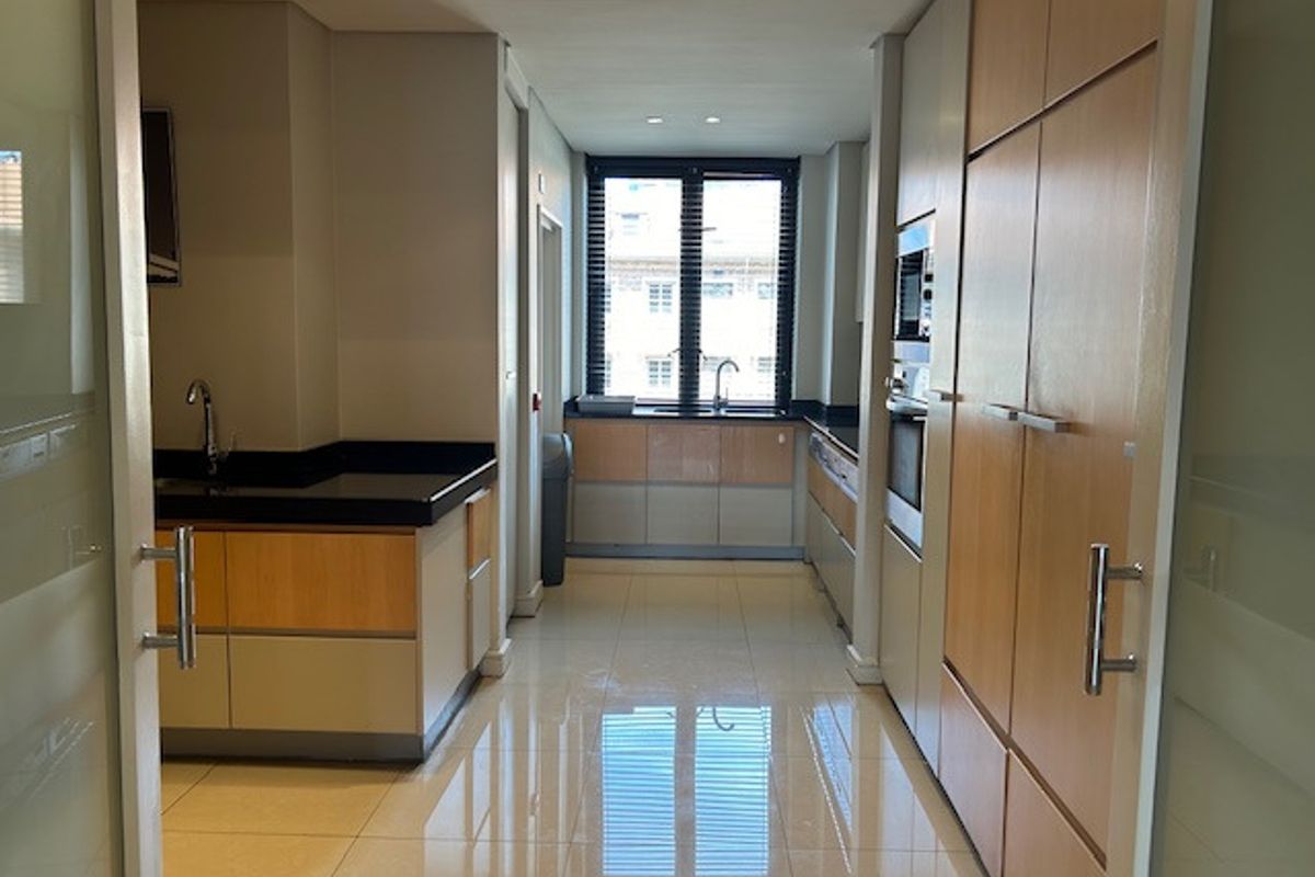 A modern, well-maintained kitchen featuring light wood cabinetry, granite countertops, integrated appliances, and polished tile flooring in a clean, open layout.